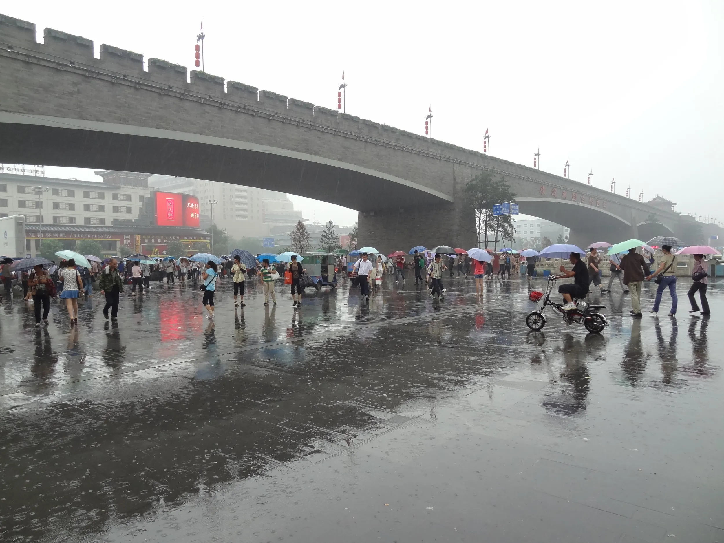 城壁の下で雨宿りする人々